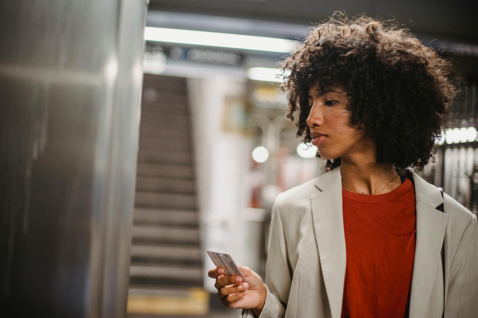 Stylish woman using a transit card in a subway station