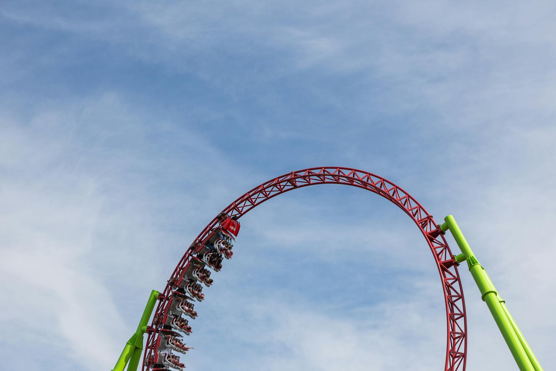 Exciting roller coaster performing a loop under a clear blue sky