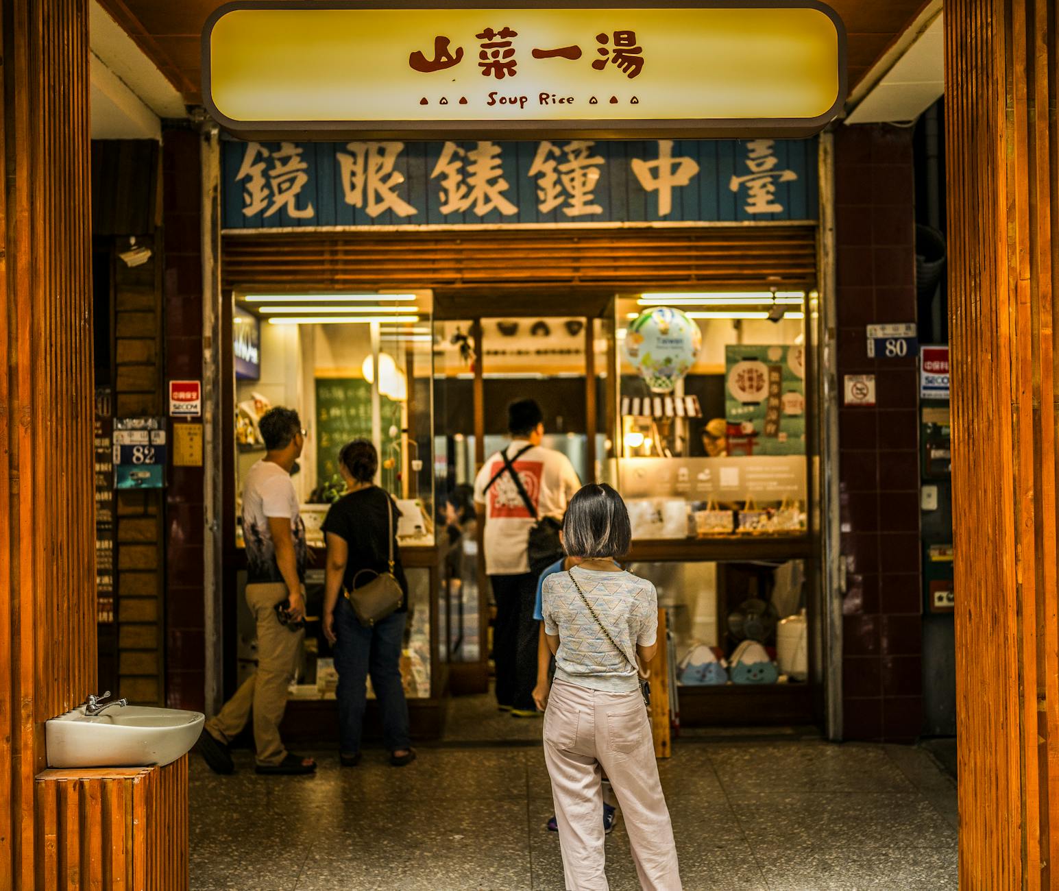Customers entering a traditional Taiwanese noodle restaurant with yellow signage