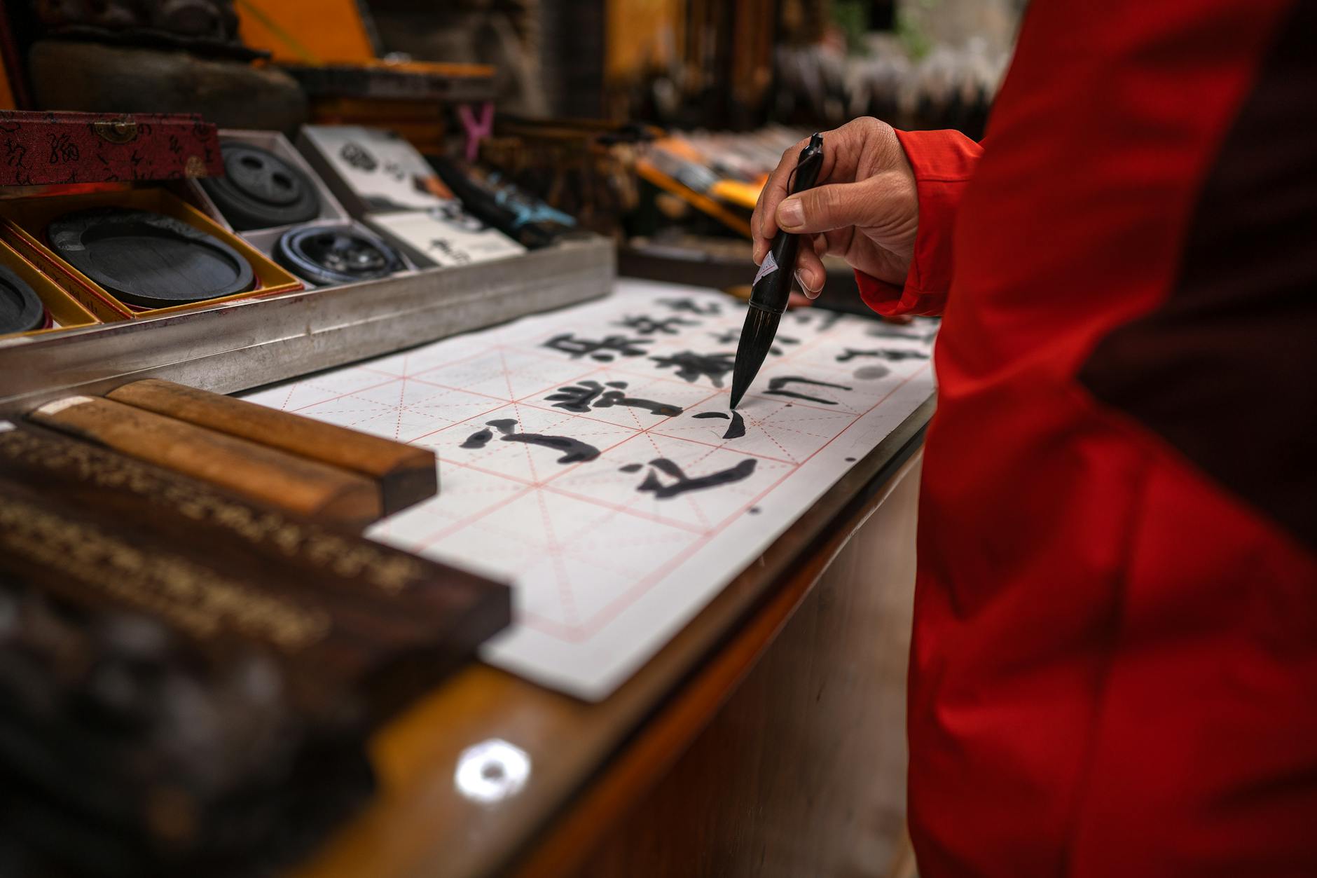 Person practicing traditional Chinese calligraphy with brush and ink