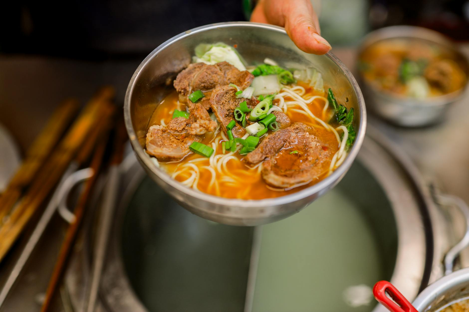 Delicious Taiwanese beef noodle soup served in a metal bowl with fresh garnishes