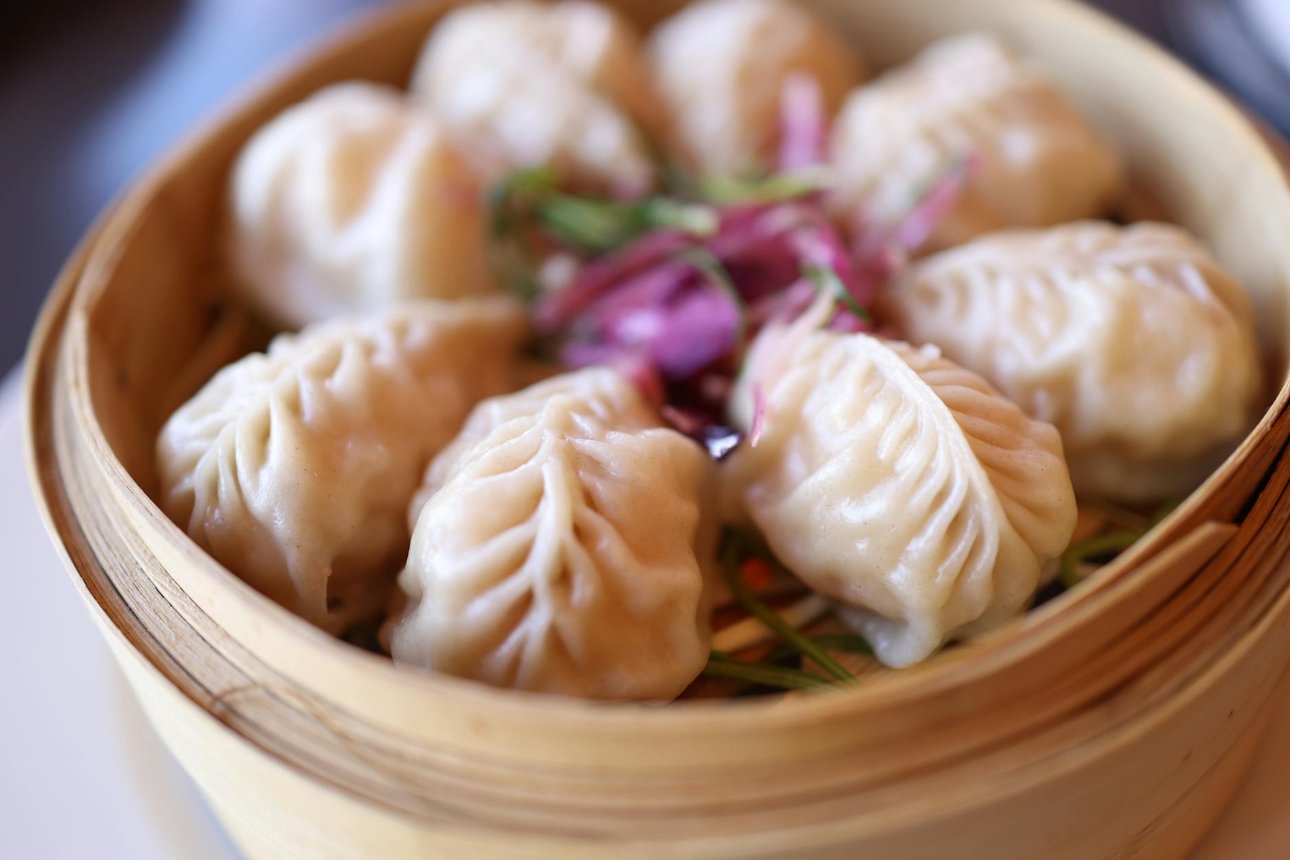 Steamed dumplings served in a traditional bamboo basket garnished with herbs