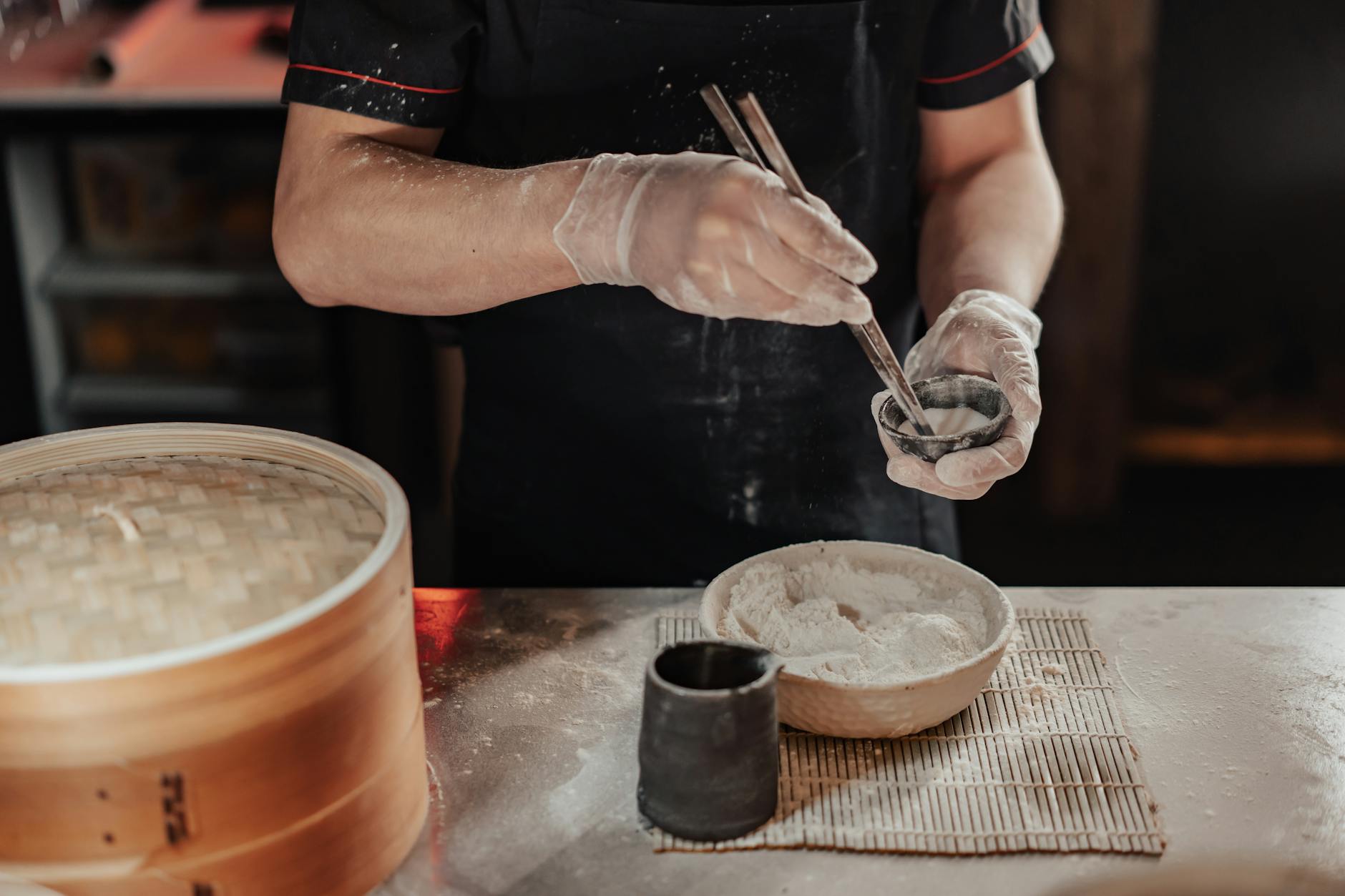 Chef wearing gloves expertly shapes dumplings using a bamboo steamer
