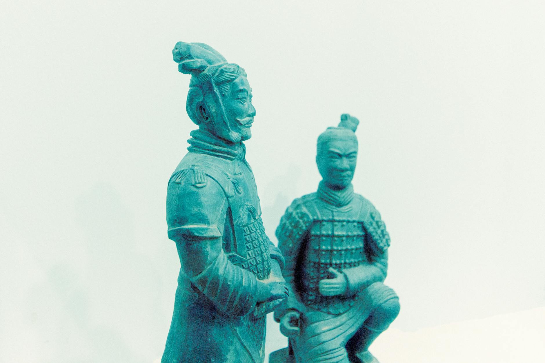 Two terracotta warrior statues displayed on a white backdrop