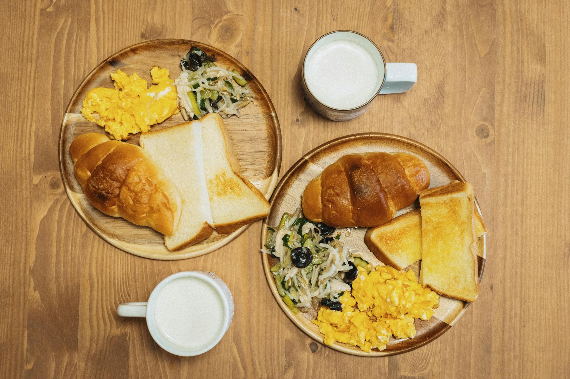 Delicious breakfast featuring eggs toast and milk on a wooden table