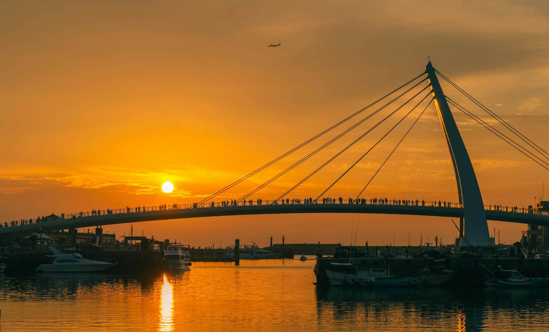 Modern cable-stayed pedestrian bridge over water at sunset