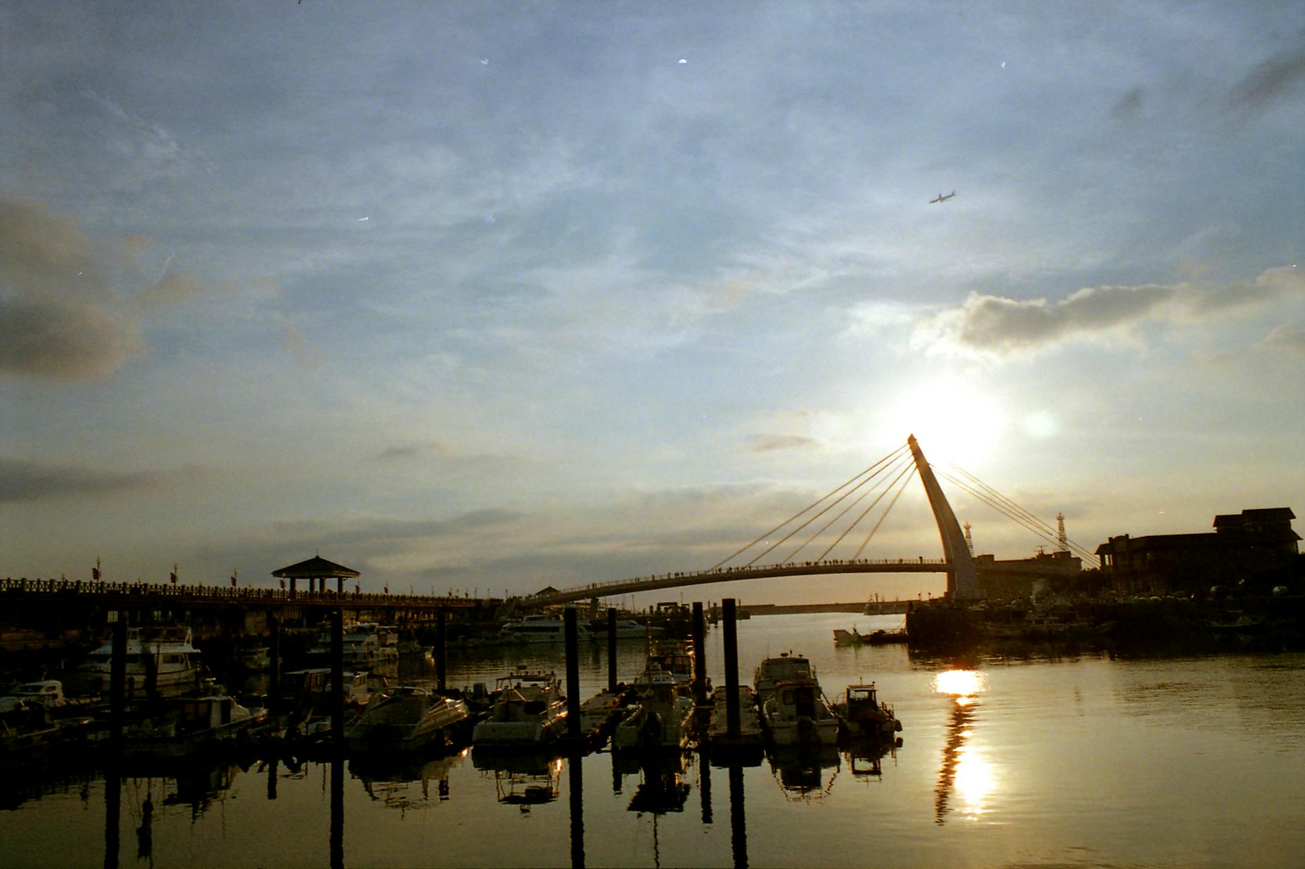 Scenic riverside town at sunset with bridge silhouette