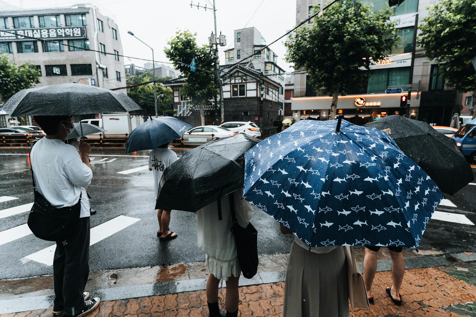 Heavy rain on Taipei streets during typhoon season with umbrellas and pedestrians