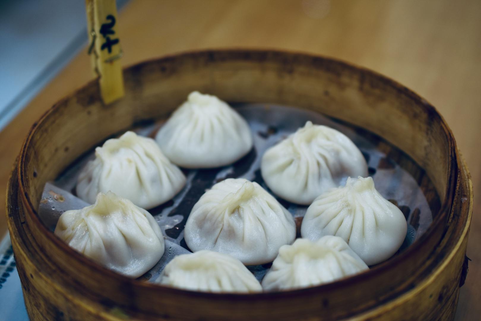 Steamed xiao long bao soup dumplings on a wooden serving tray at a Taipei family restaurant