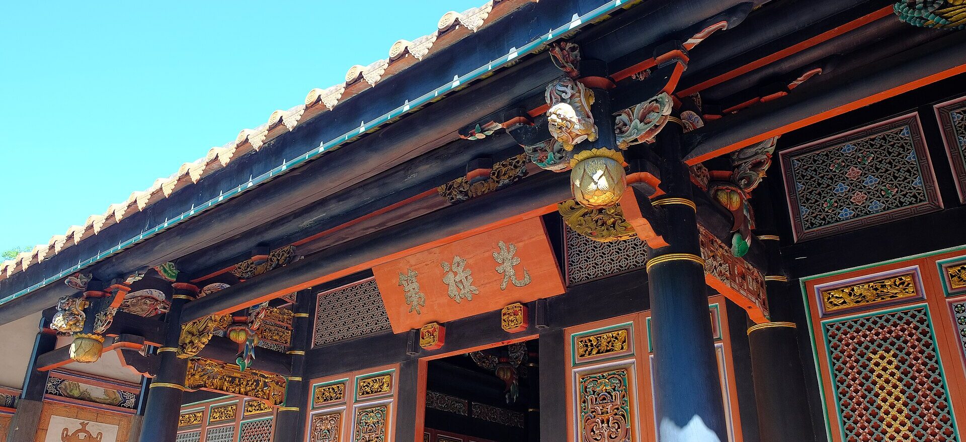 Carved and painted brackets, black columns and lattice doors on the front hall of the Three-Courtyard Residence at the Lin Family Mansion and Garden in Banqiao, under a plaque reading 光祿第
