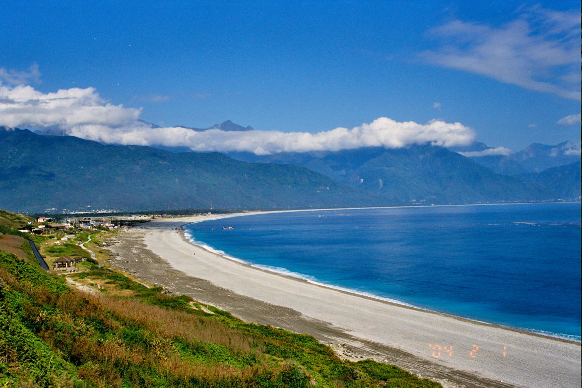 The long grey pebble crescent of Qixingtan beach curving away below green mountains near Hualien