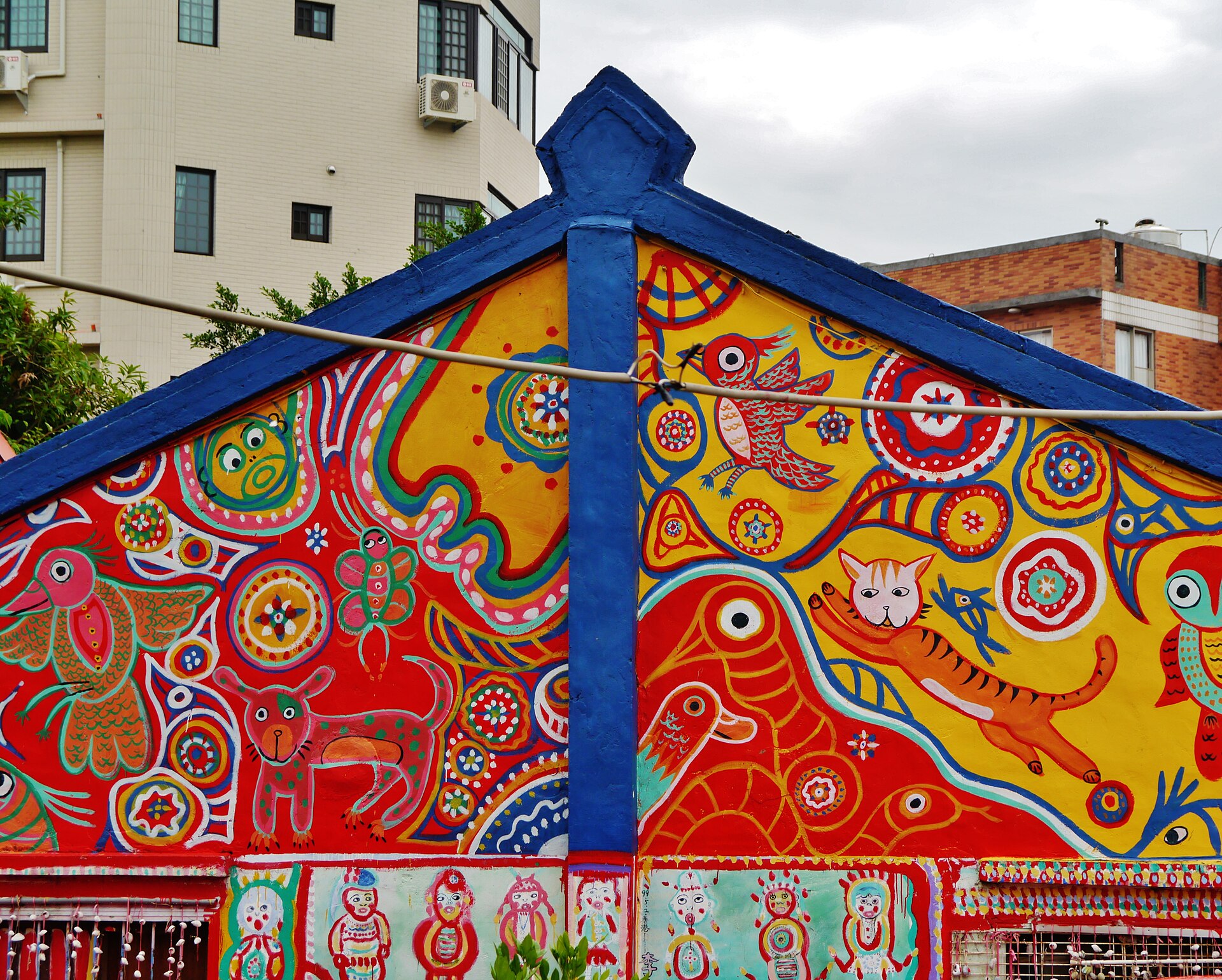 A brightly painted gable end at Taichung's Rainbow Village covered in figures, birds and animals