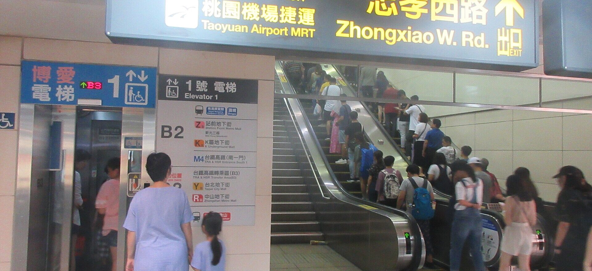 Commuters standing single file on the right of a busy escalator at Taipei Main Station