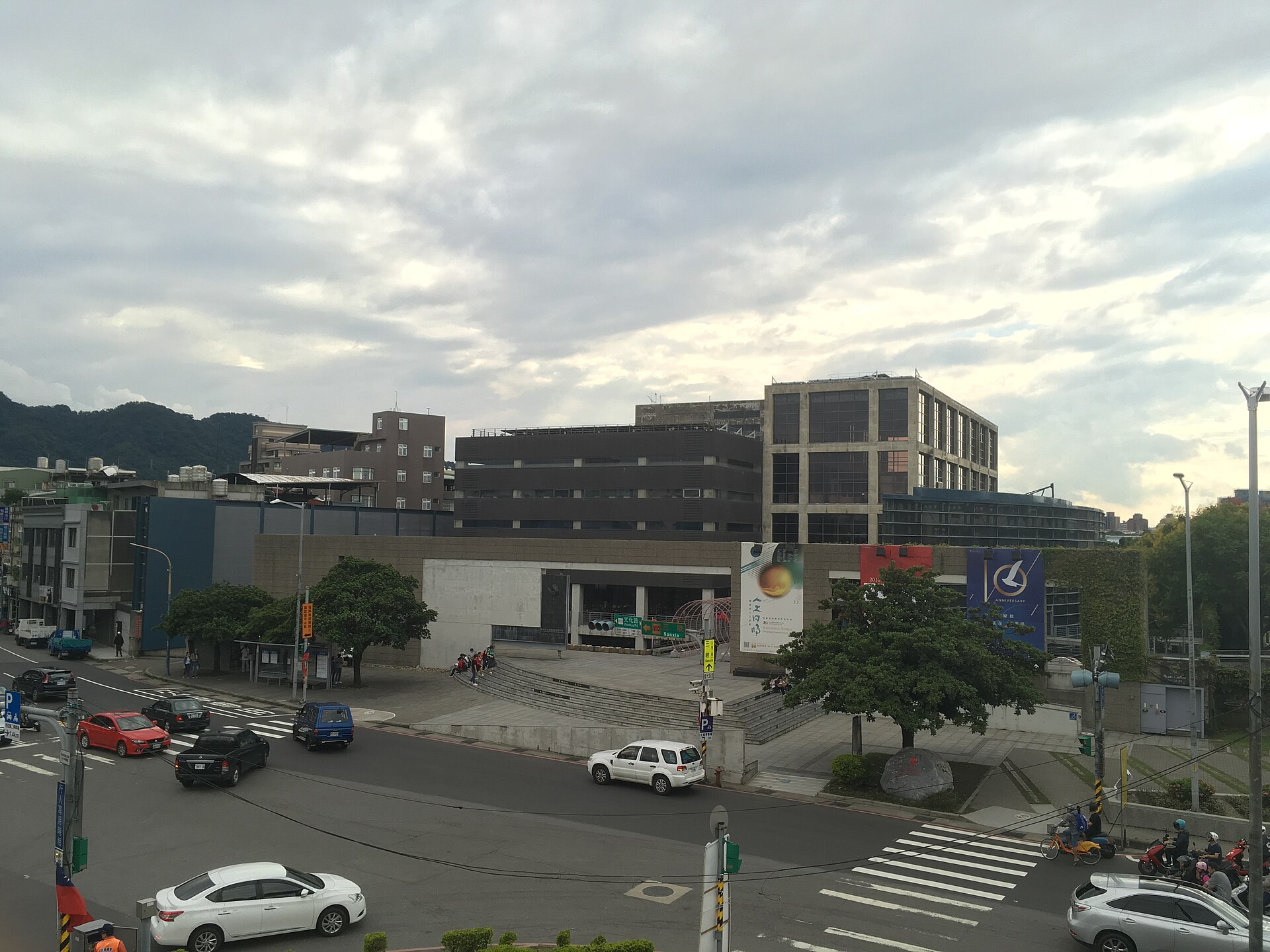 The low concrete and glass building of the Yingge Ceramics Museum seen across a road junction under a grey sky