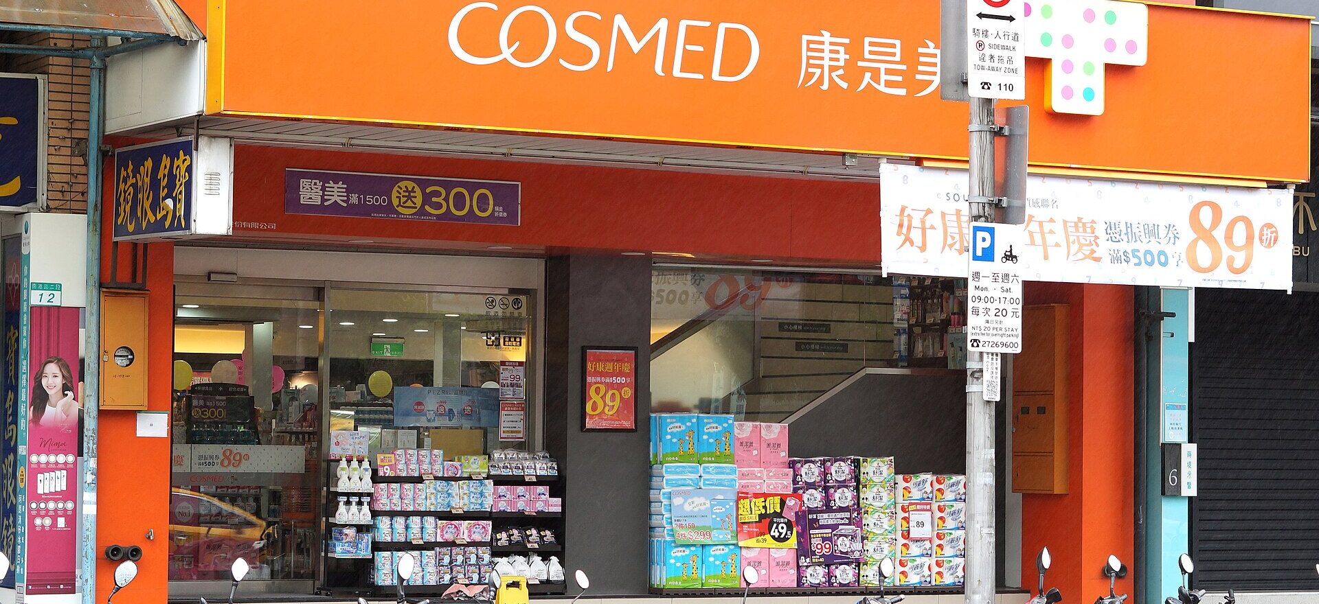 Cosmed's orange Jiale storefront in Taipei has an open entrance and stacked packaged goods behind a row of parked scooters.