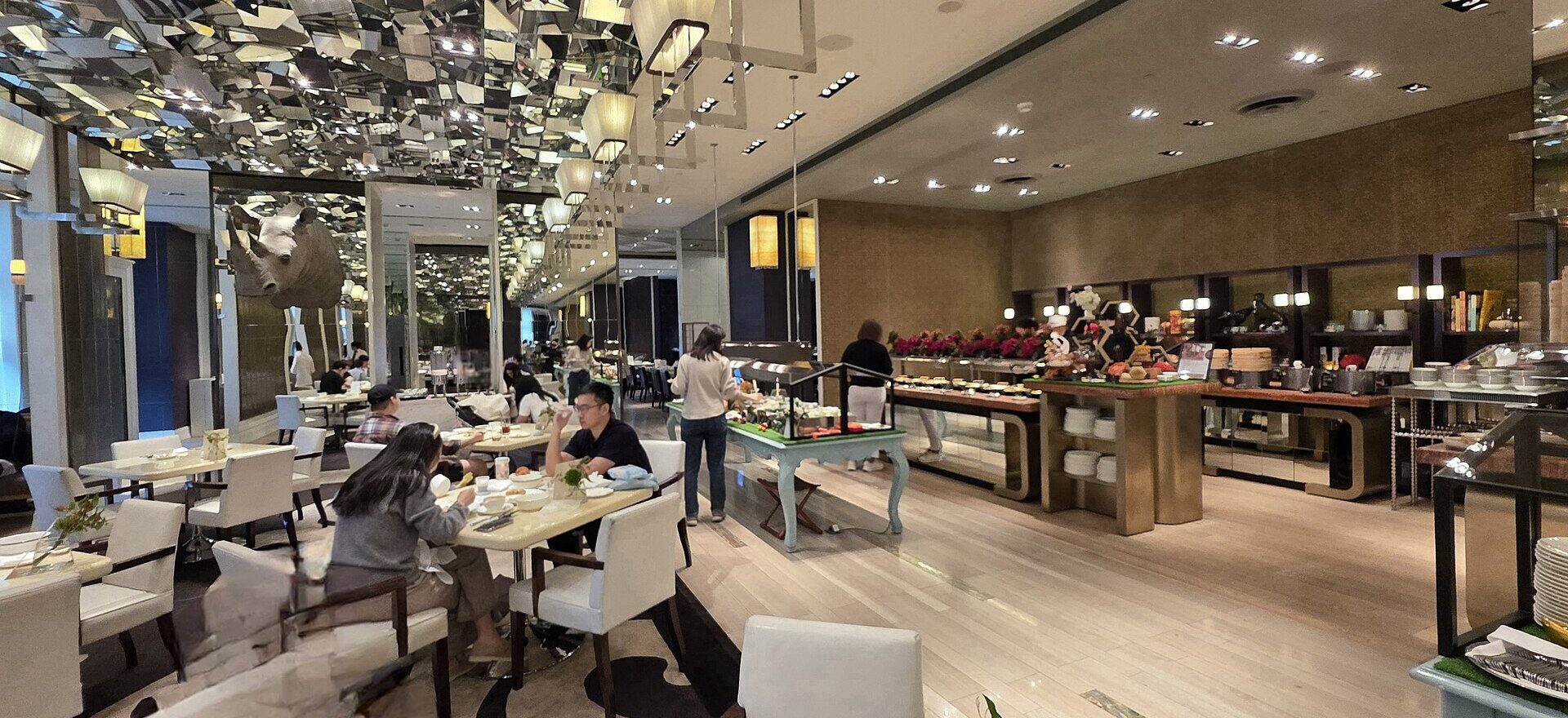 Diners sit beside buffet counters beneath a mirrored ceiling at Cafe Un Deux Trois in Taipei.