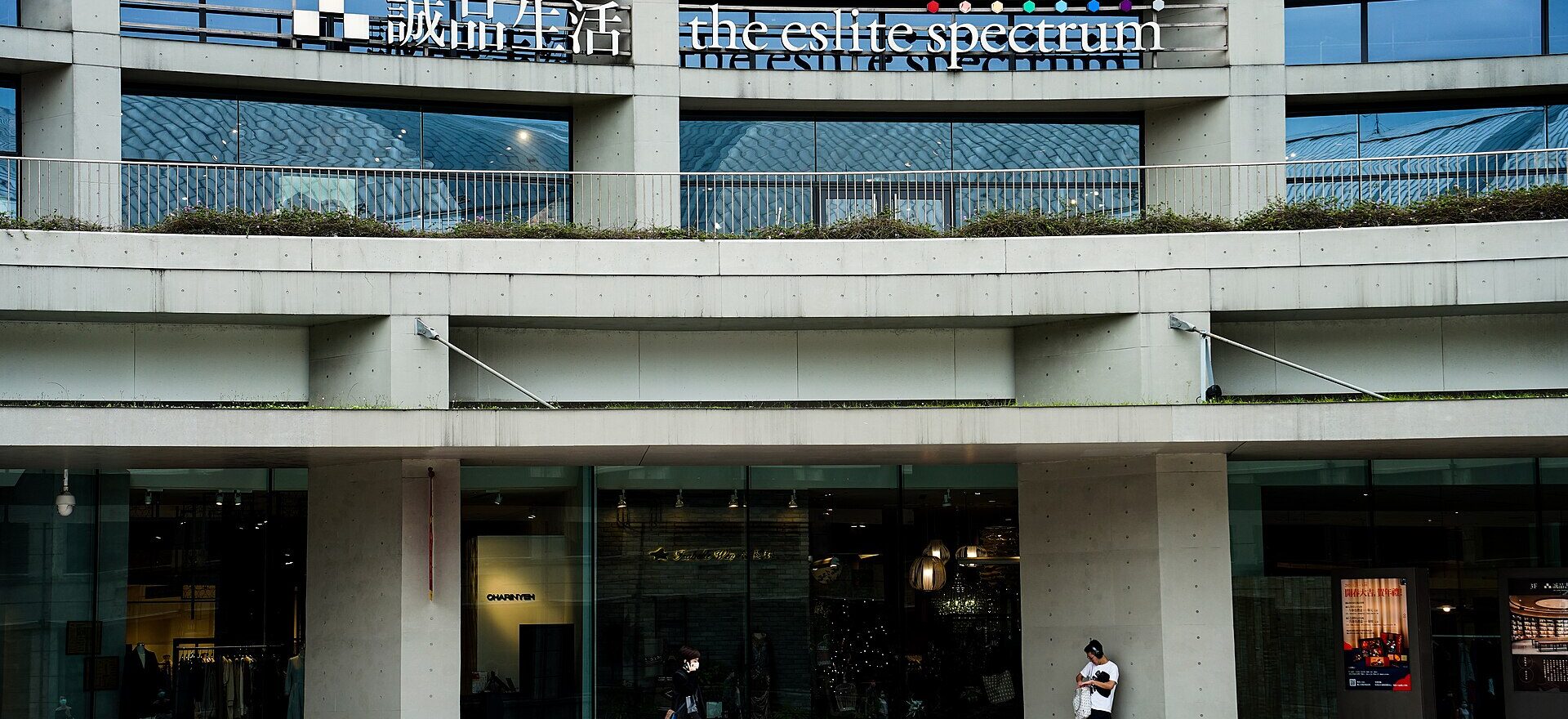 Eslite Spectrum Songyan in Taipei, with its curved concrete facade and pedestrians outside the ground-floor shops.