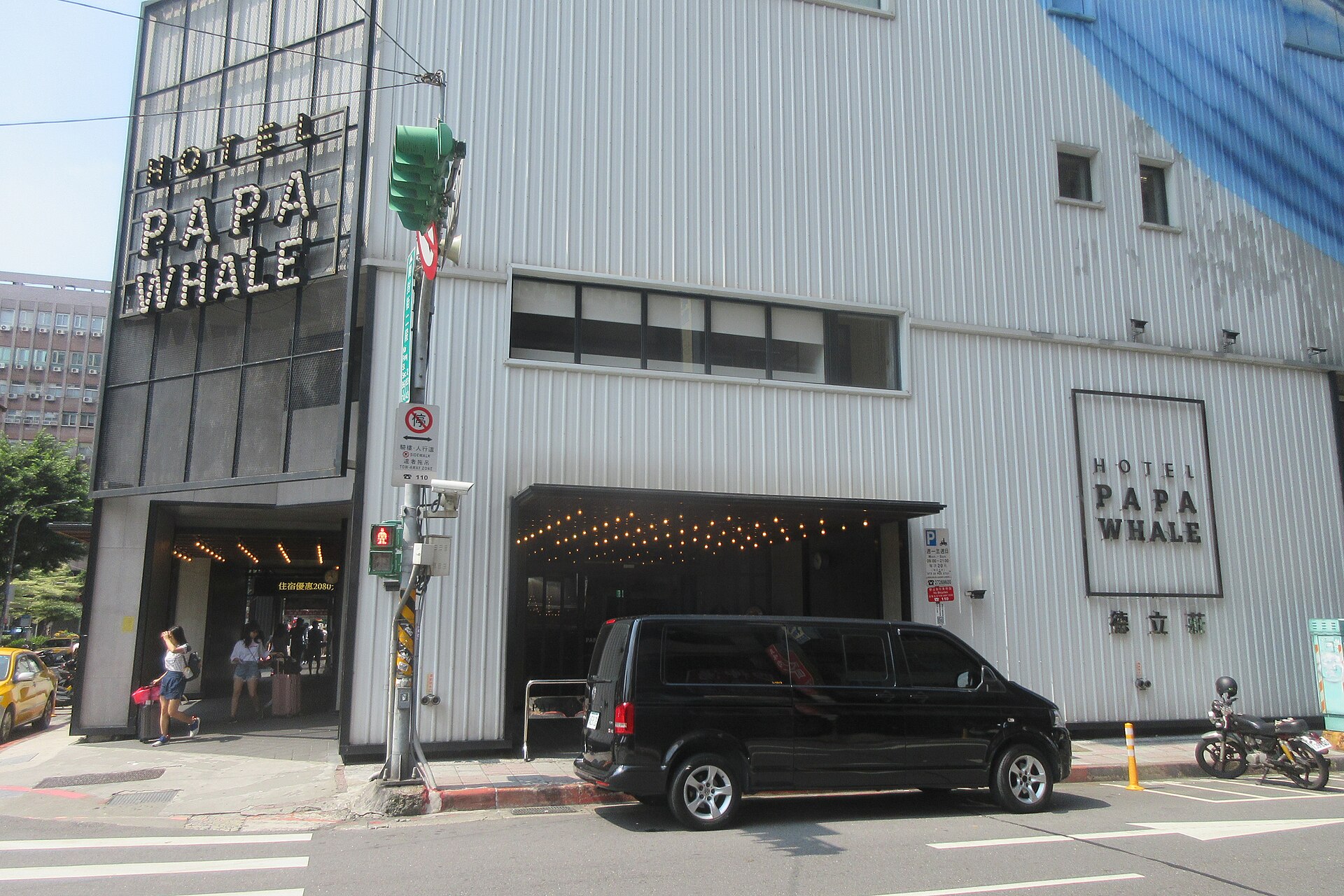 Hotel Papa Whale in Taipei has a corrugated facade, large entrance lettering and warm lights above the sidewalk.