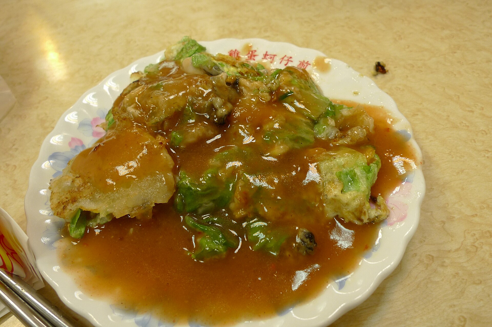 An oyster omelette covered in glossy sauce and green leaves fills a plate at Taipei Ningxia Night Market.