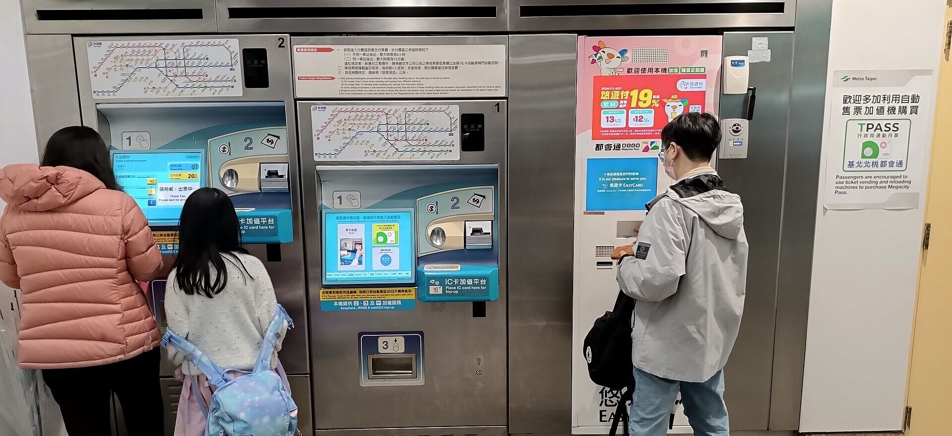Passengers use ticket and EasyCard machines beneath bilingual signs at Taipower Building Station in Taipei.