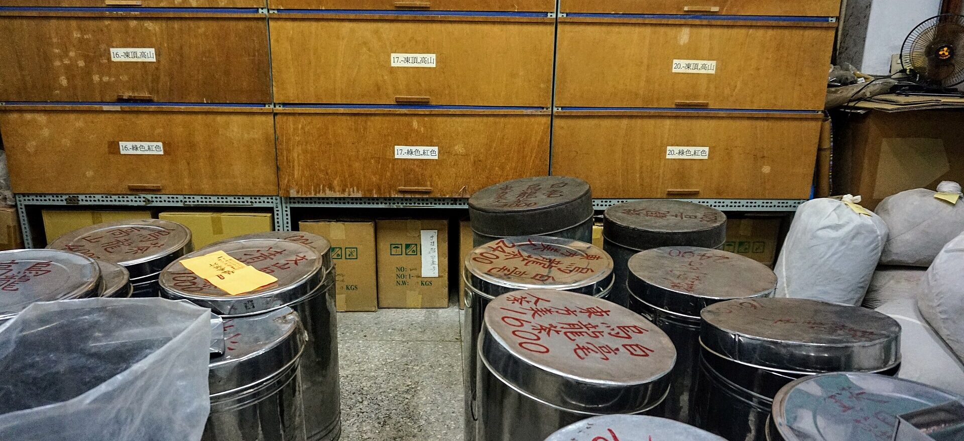 Rows of large metal tea tins stand before wooden storage drawers at Lin Hua Tai Tea Shop in Taipei.