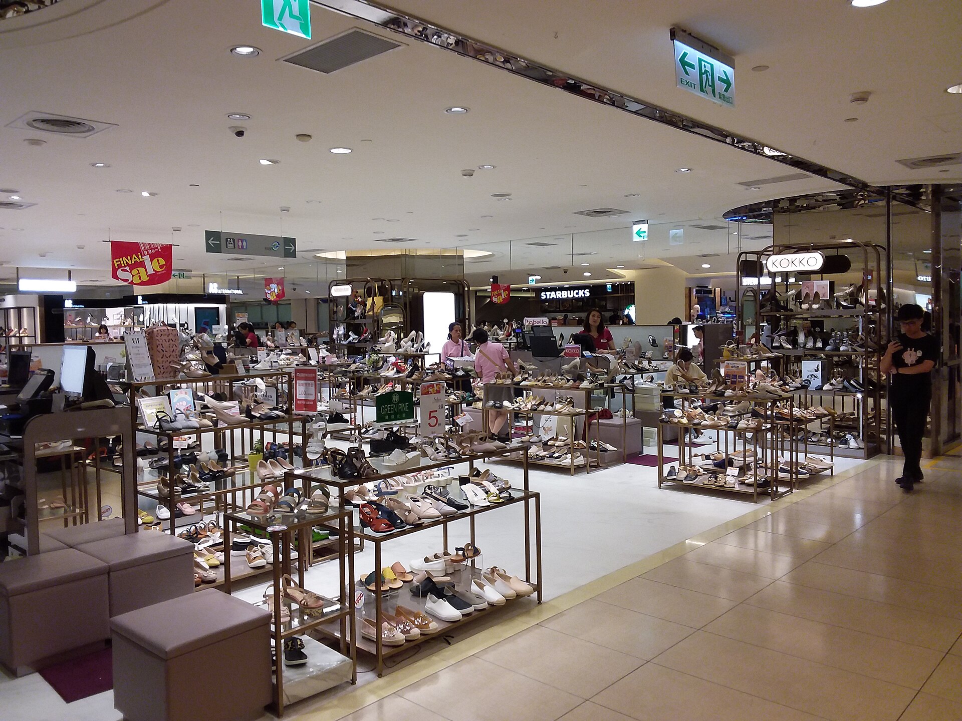 Shoppers browse shoe displays and low racks inside the brightly lit Pacific SOGO Fuxing department store in Taipei.