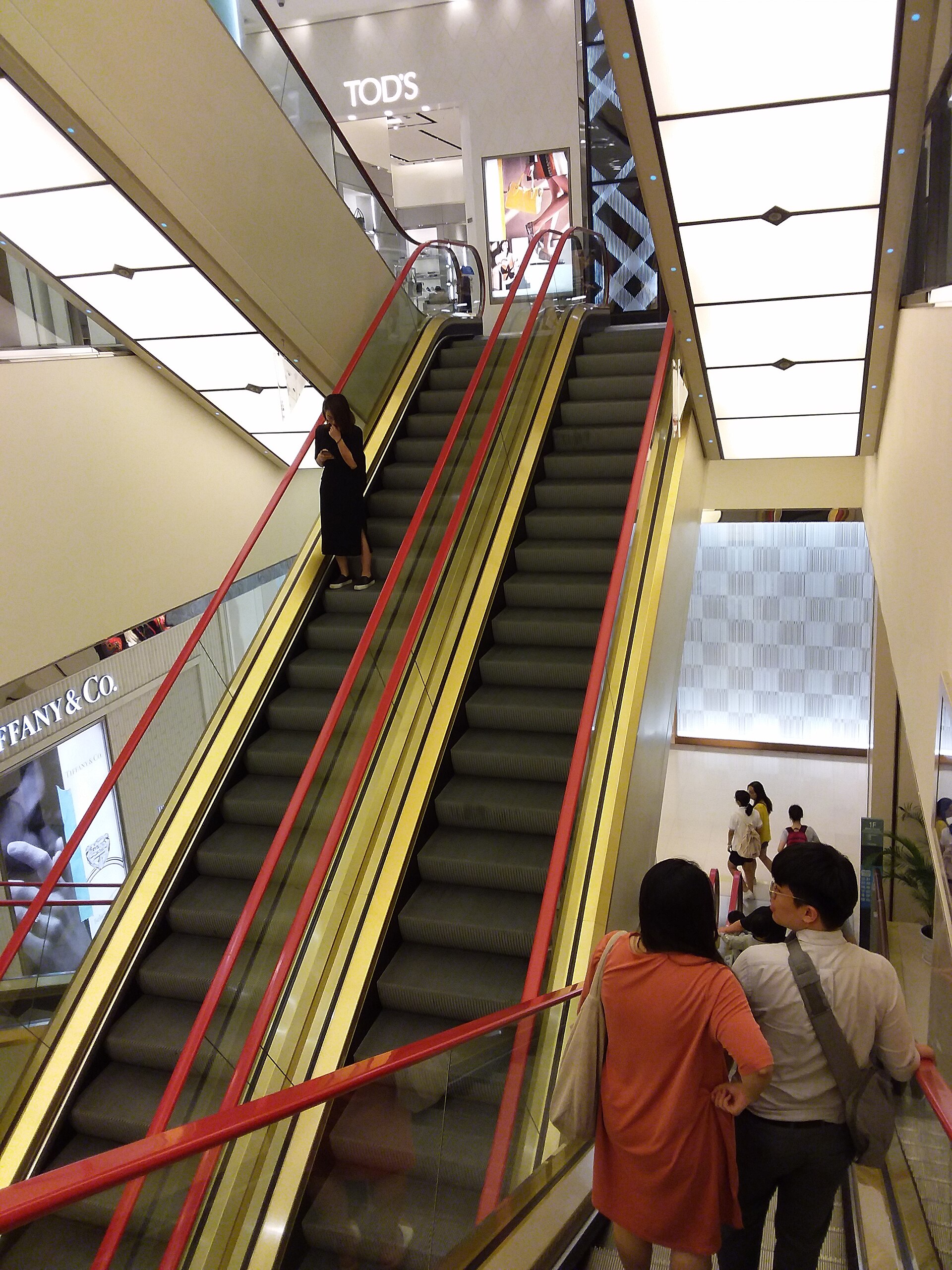 Shoppers ride red-railed escalators between brightly lit floors inside Taipei’s Pacific SOGO Fuxing department store.