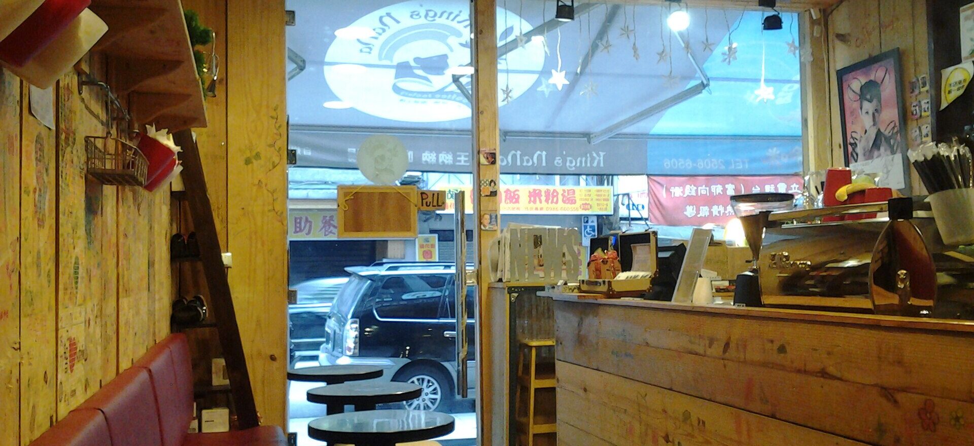Small tables line a red bench beside the espresso counter at King's Nana Coffee Factory in Taipei.