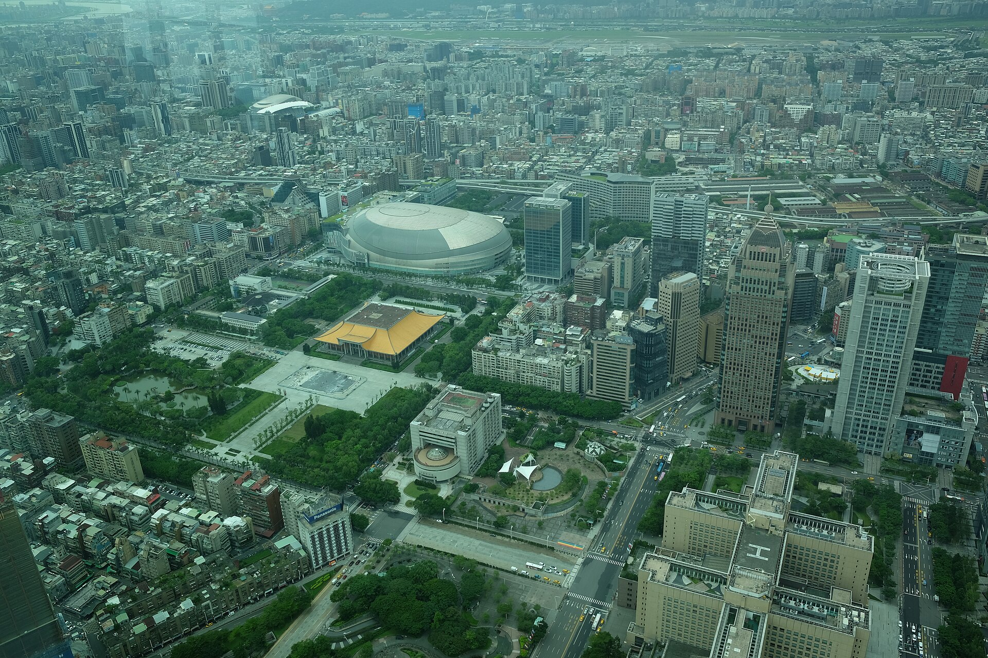 Taipei City Hall, a yellow-roofed memorial hall and dense city blocks spread below the windows of Taipei 101 Observatory.