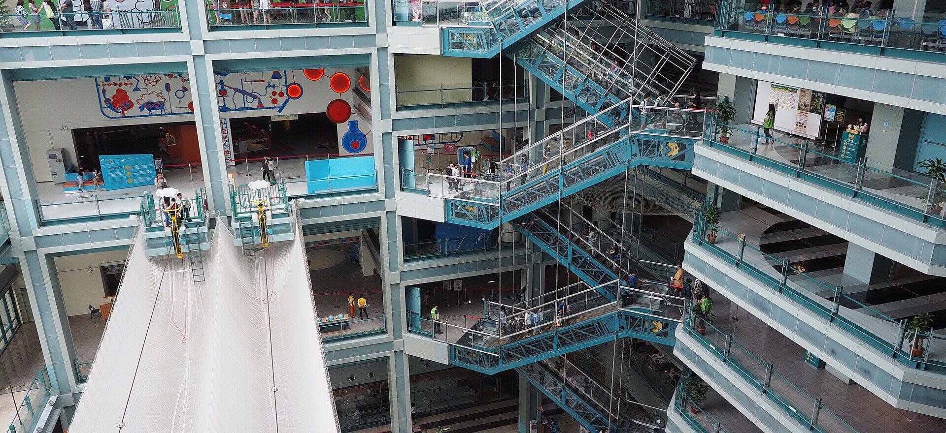 Zigzag staircases connect balconies around the tall indoor atrium of Taipei's National Taiwan Science Education Center, with visitors on several levels.